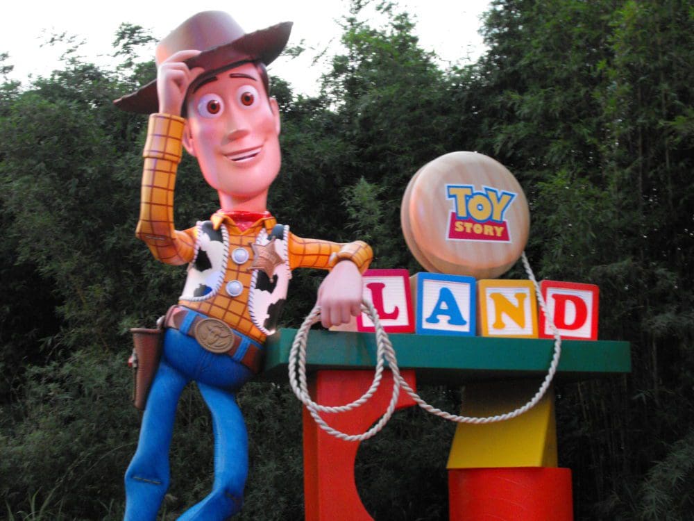 A toy story character is standing next to the land sign.