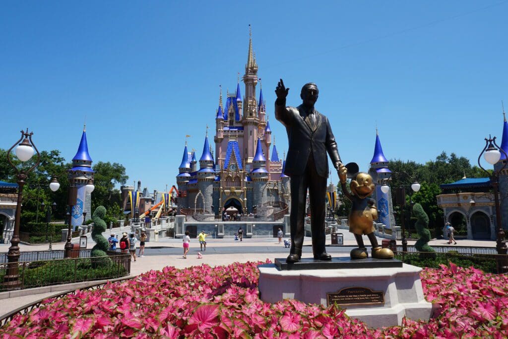 A statue of walt disney in front of the castle.