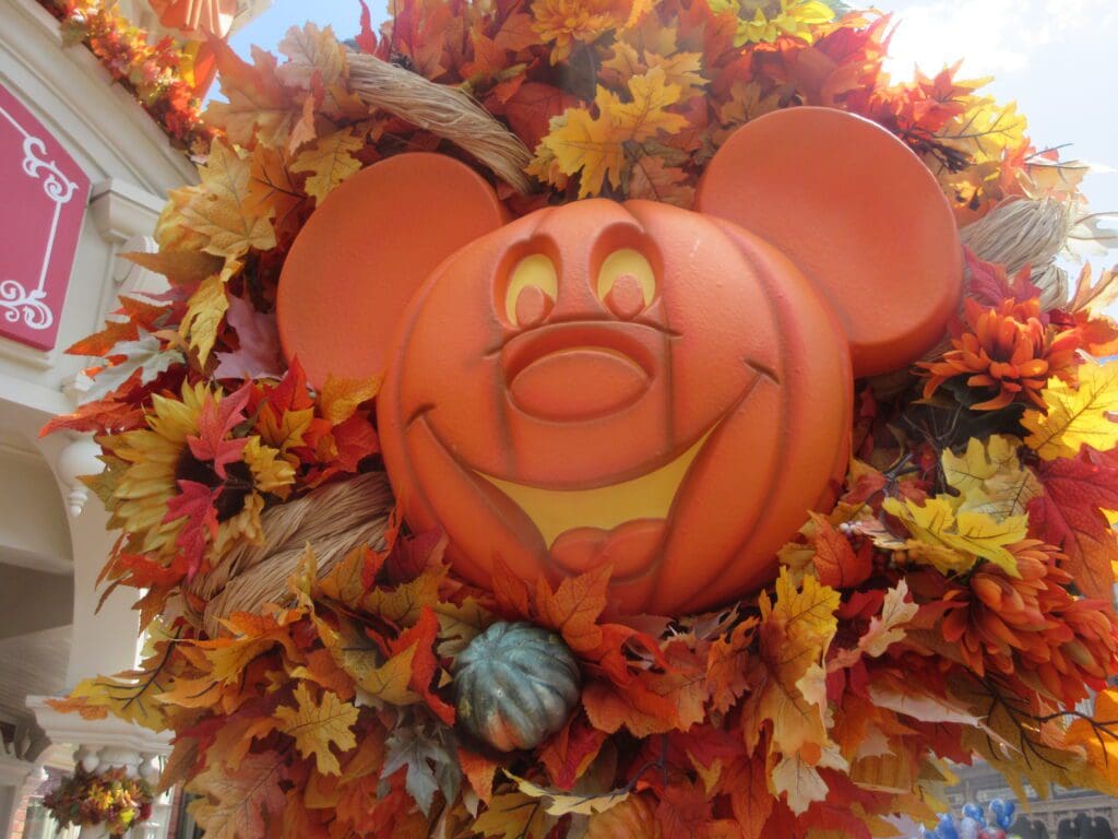 A mickey mouse pumpkin sitting on top of a wreath.