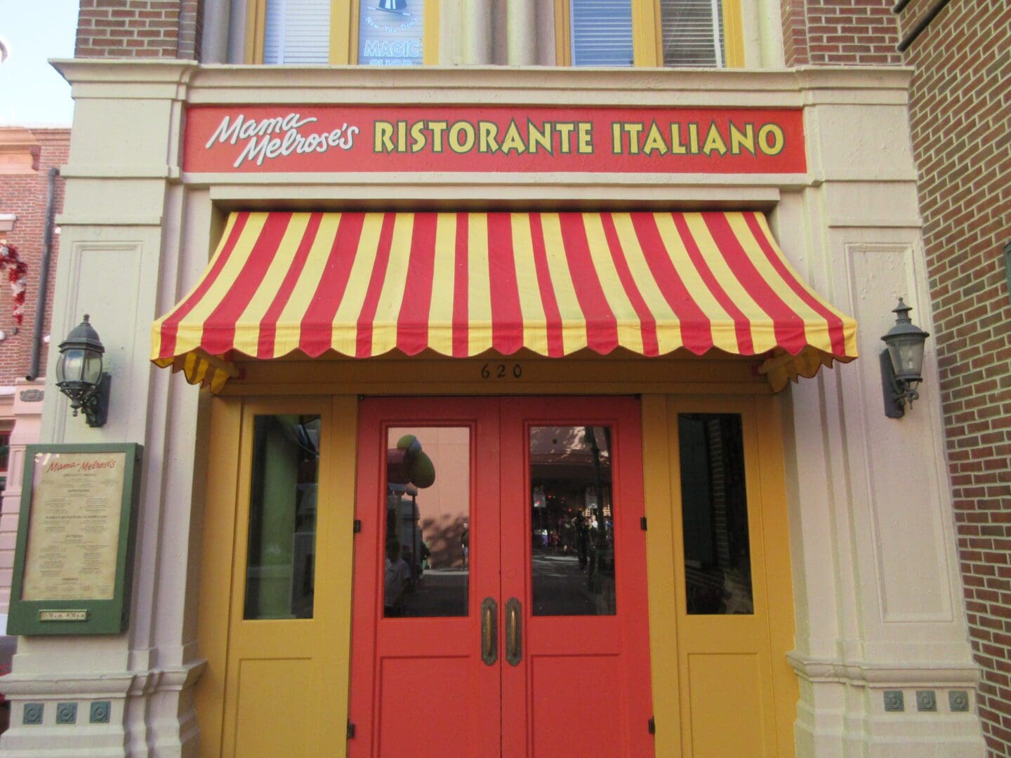 A restaurant with red and yellow awnings on the front.