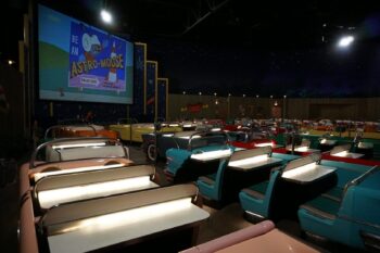A row of seats in front of an open air movie screen.