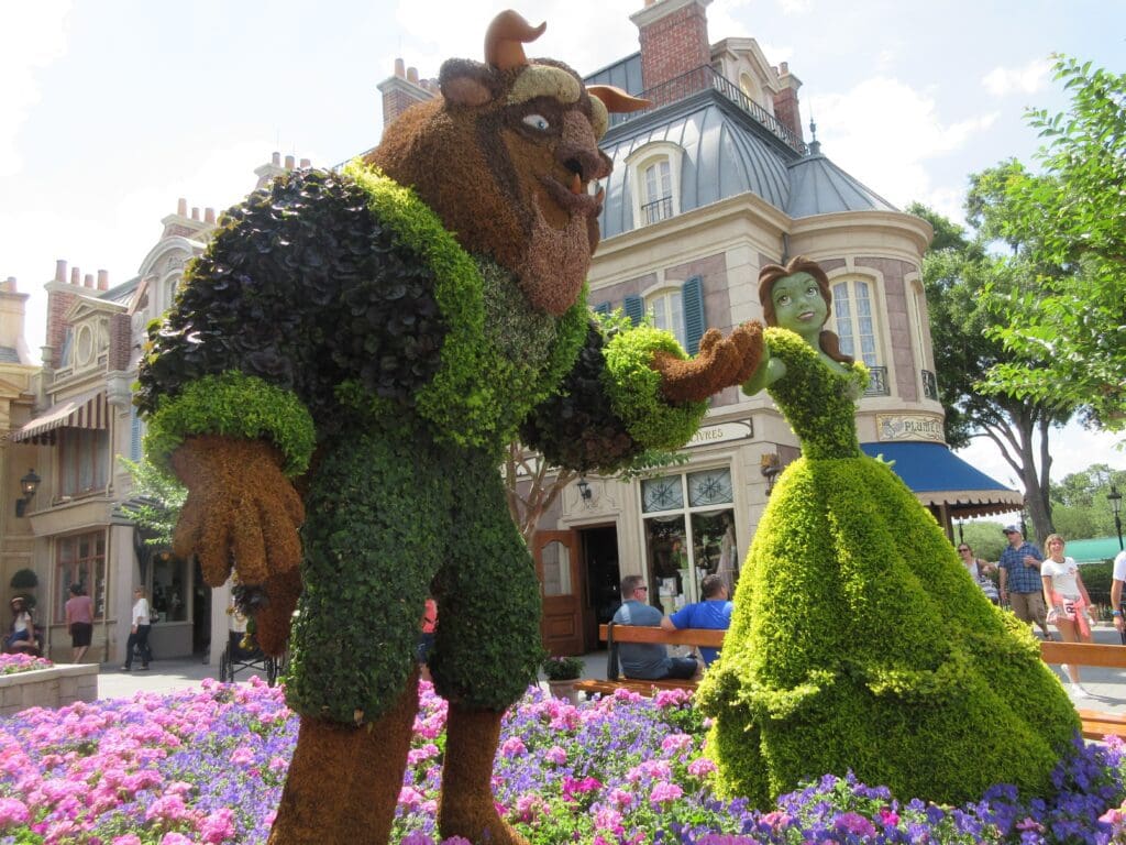 A man and woman in topiary form next to flowers.